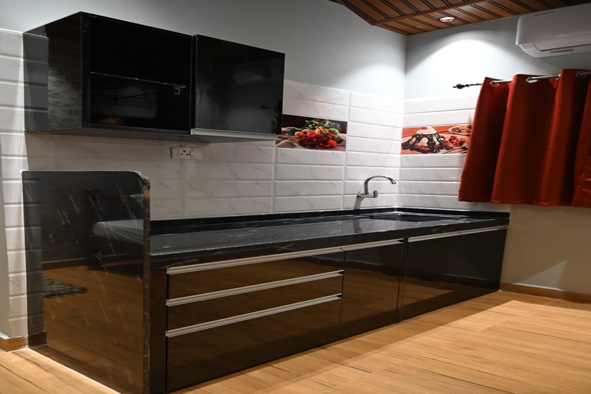 A kitchen with a black countertop, white tiled backsplash, and a red curtain.
