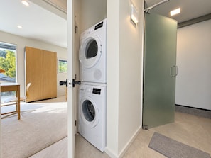 A laundry room with two stacked washing machines, a wooden door, and a view of the outdoors. - Private 1BR Suite near Steveston | Living Room, No Kitchen (Richmond)