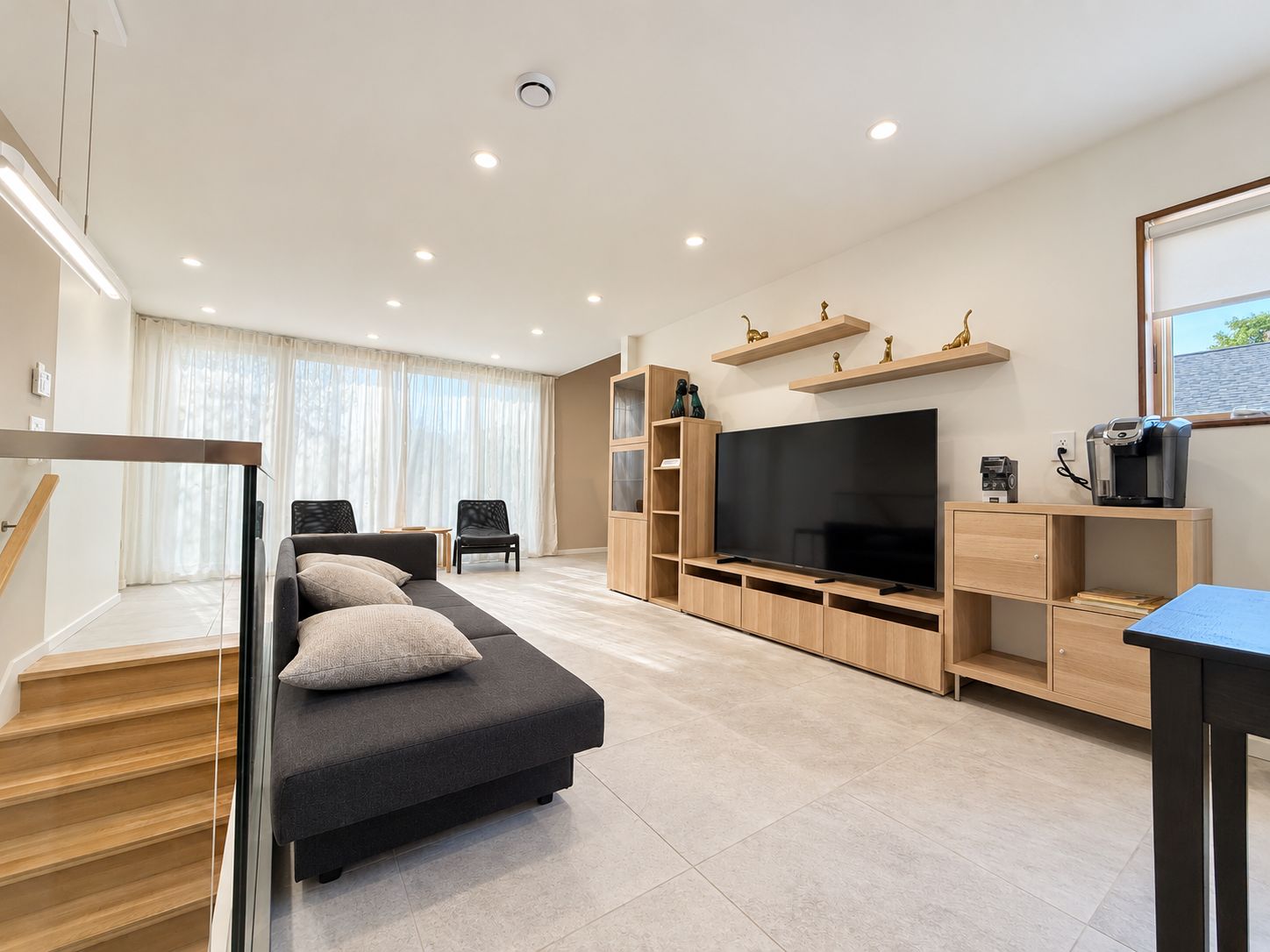 A modern living room with a sofa, TV, and built-in shelves.
