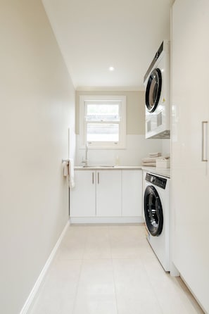 A compact kitchen with white cabinets, a built-in washing machine, and a window above the sink. - Waterfront Geelong - Bay View Bliss
Geelong CBD at your doorstep (Geelong)