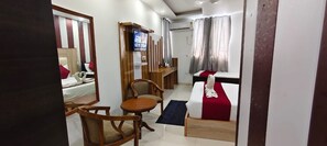 Ein Hotelzimmer mit Bett, Fernseher, Schreibtisch und Stuhl.