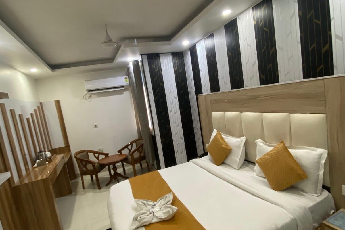 A hotel room with a bed, bedside table, and a desk with chairs.
