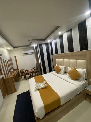 A hotel room with a bed, bedside table, and a desk with chairs. - Hotel Modesty - Mahipalpur Delhi (New Delhi)