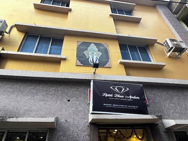 A building with a sign for Hotel Blue Amber, indicating it offers rooms, a restaurant, and a banquet.