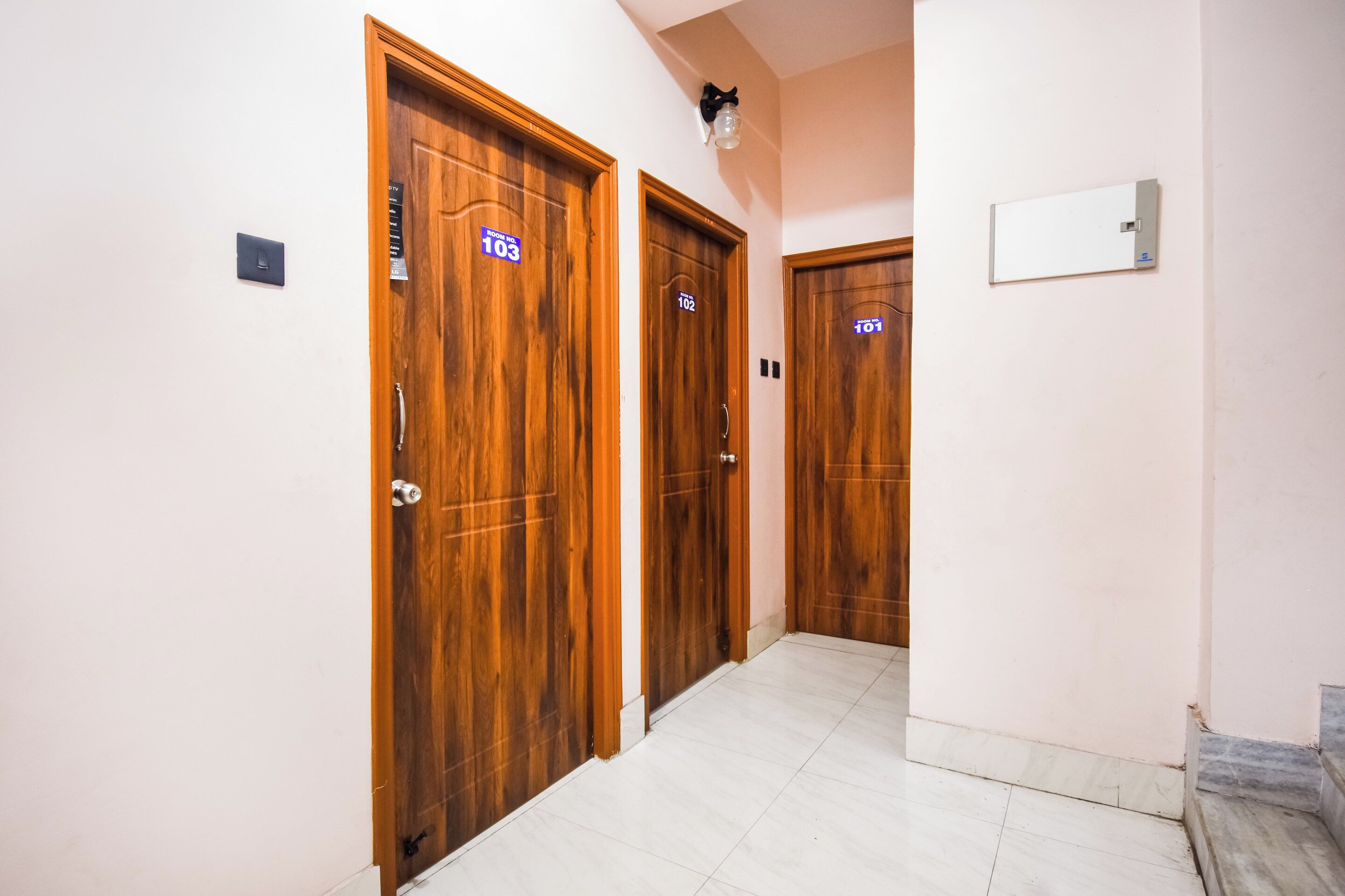 Un pasillo con puertas de madera, cada una con un número de habitación.