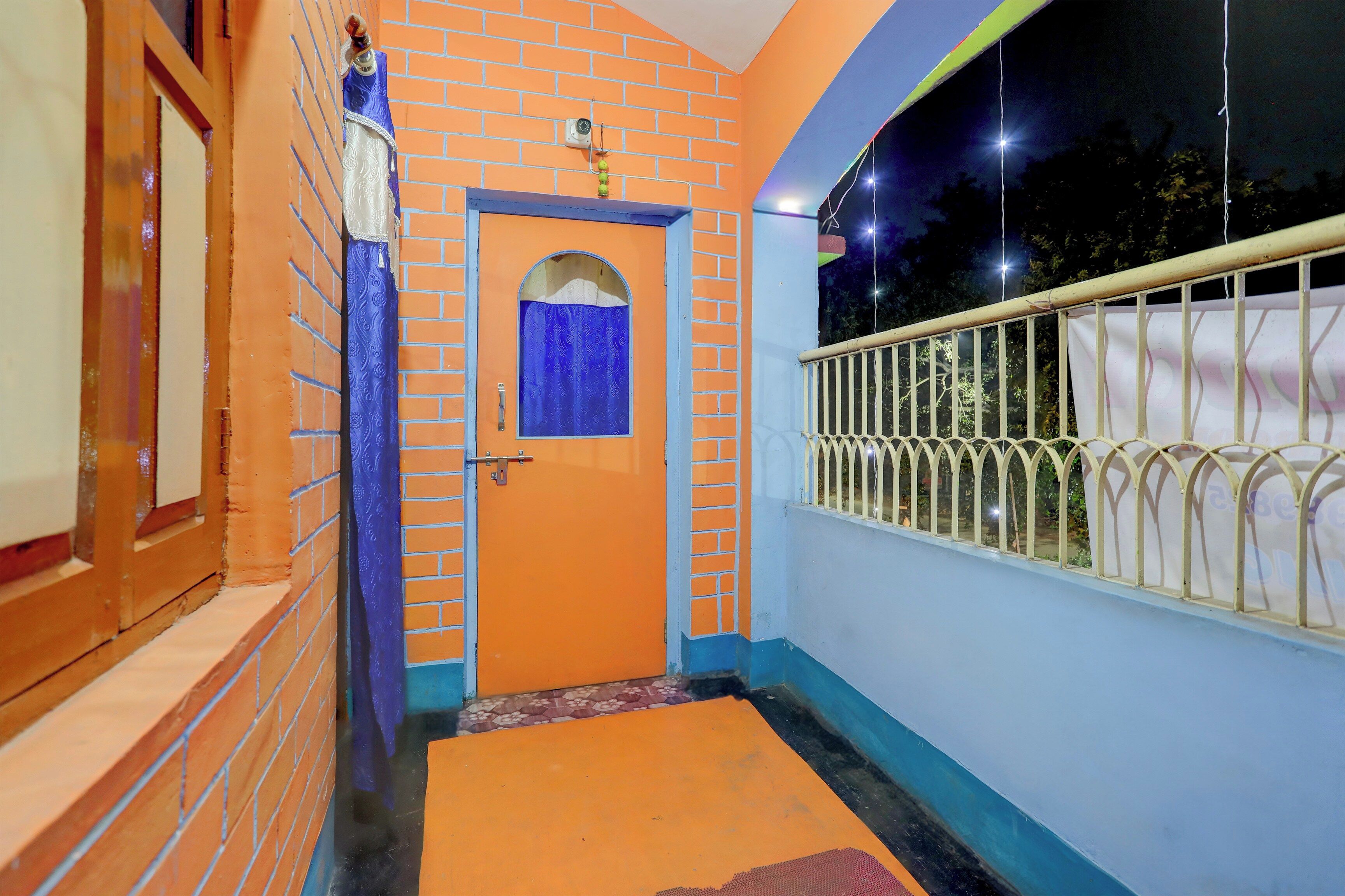 Un pasillo con una puerta, una ventana con cortina y una barandilla.