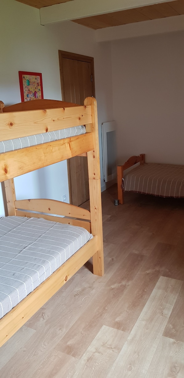 Une chambre avec un lit superposé, une télévision et une porte.