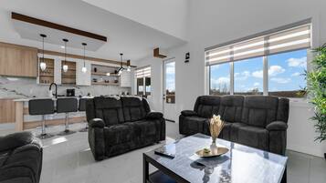 Een moderne woonkamer met een bank, twee fauteuils en een salontafel.