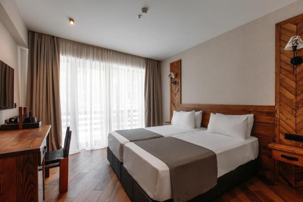 A hotel room with a large bed, a desk, and a chair.