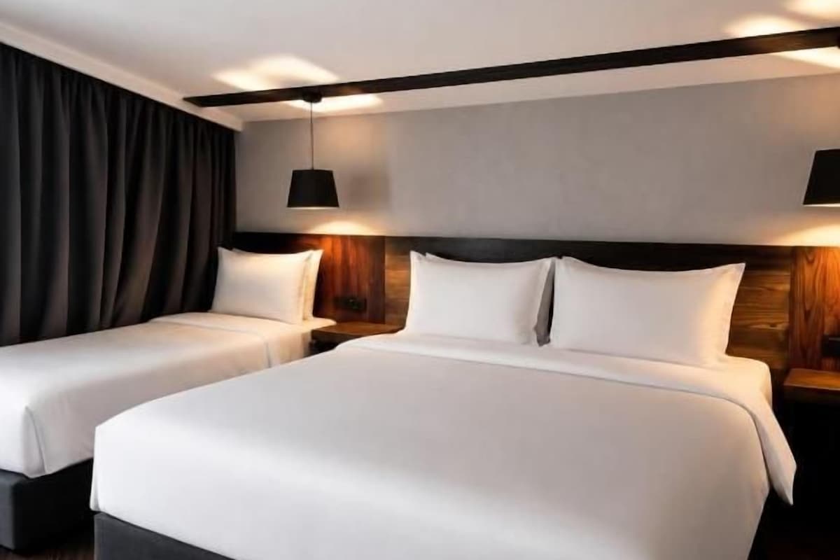 A hotel room with a large bed, two bedside tables, and a dark curtain.