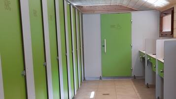 A row of green and white lockers with a tiled floor and a ceiling with recessed lighting.