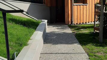A pathway leading to a building with a stone facade and a wooden deck.
