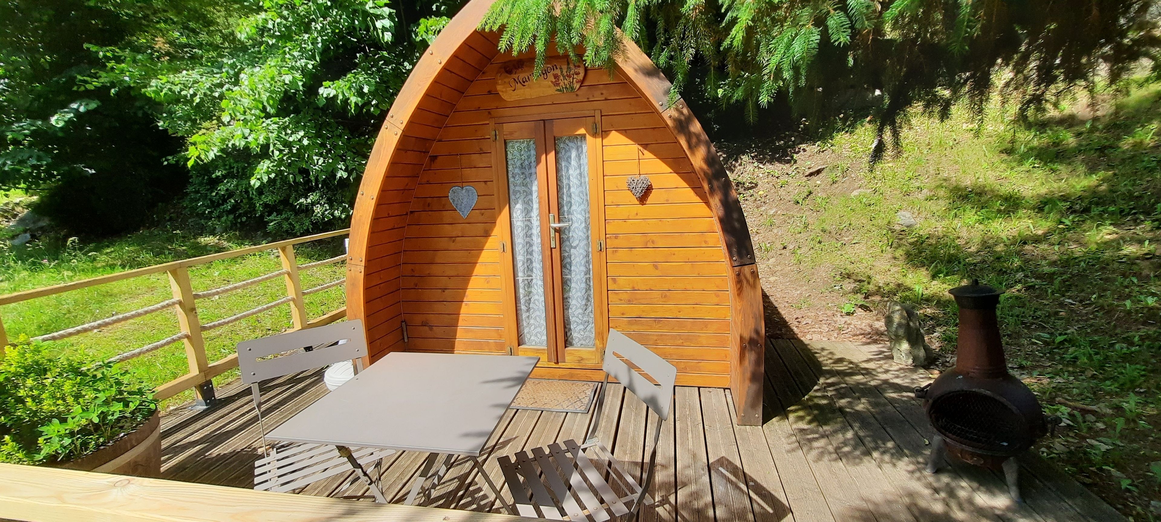 Een houten vakantiehuisje met een deur, een tafel en een stoel buiten.
