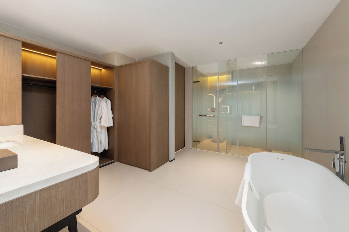 Un baño moderno con una bañera independiente, ducha con cerramiento de vidrio y tocador de madera con espejo.