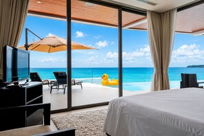 Ett hotellrum med en stor säng, en TV, ett skrivbord och utsikt över havet.