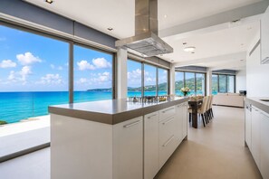 A modern kitchen with a large island, ample natural light, and a view of the ocean. - Cape Sienna Villa 4: 5BR Waterfront Luxury, 22m Infinity Pool & Housekeeping (Kathu)