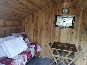 A wooden cabin room with a bed, a small table, and a window with a picture. - Cabin 'Gavarnie, Sanitaire Camping' with Mountain View, Private Terrace and Wi-Fi (Gavarnie-Gèdre)