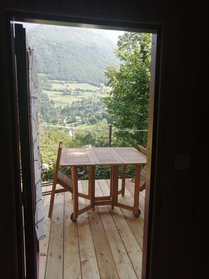 A wooden deck with a table and chairs, overlooking a valley with greenery and buildings. - Cabin 'Gavarnie, Sanitaire Camping' with Mountain View, Private Terrace and Wi-Fi (Gavarnie-Gèdre)