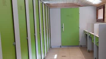 Een rij groene en witte kluisjes met een betegelde vloer en een plafond met inbouwverlichting.