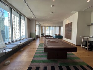 A modern hotel room with large windows, a pool table, a sofa, and a dining area. - Resort-Style Pool + Gym + Sauna | Walk to Brightline | Miami Oasis at The Crosby (Miami)