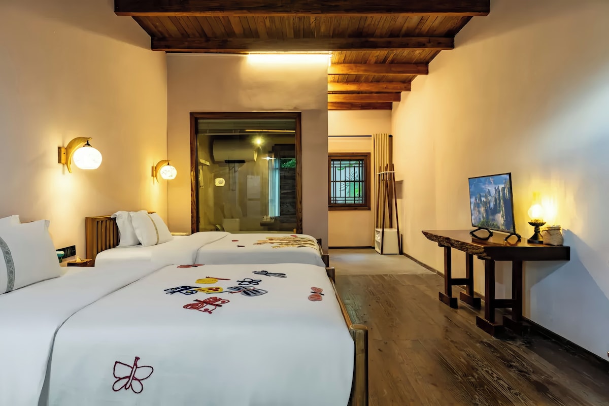 Een hotelkamer met twee bedden, een bureau met een computer en een schilderij aan de muur.