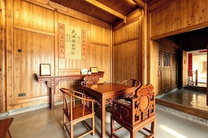 Een klassiek houten interieur met een eettafel en stoelen, een houten plafond en een muur met een ingelijst certificaat.