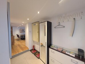 A reception area with a 'Welcome' sign, a coat rack, a fire extinguisher, and a counter with brochures. - Holiday Apartment 'Gurgltal' (Nassereith)