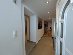 A hallway with a door on the right, a painting on the wall, and a kitchen area in the background. - Holiday Apartment 'Gurgltal' (Nassereith)