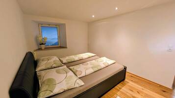 A bedroom with a bed, a window with a view, and a white rug.