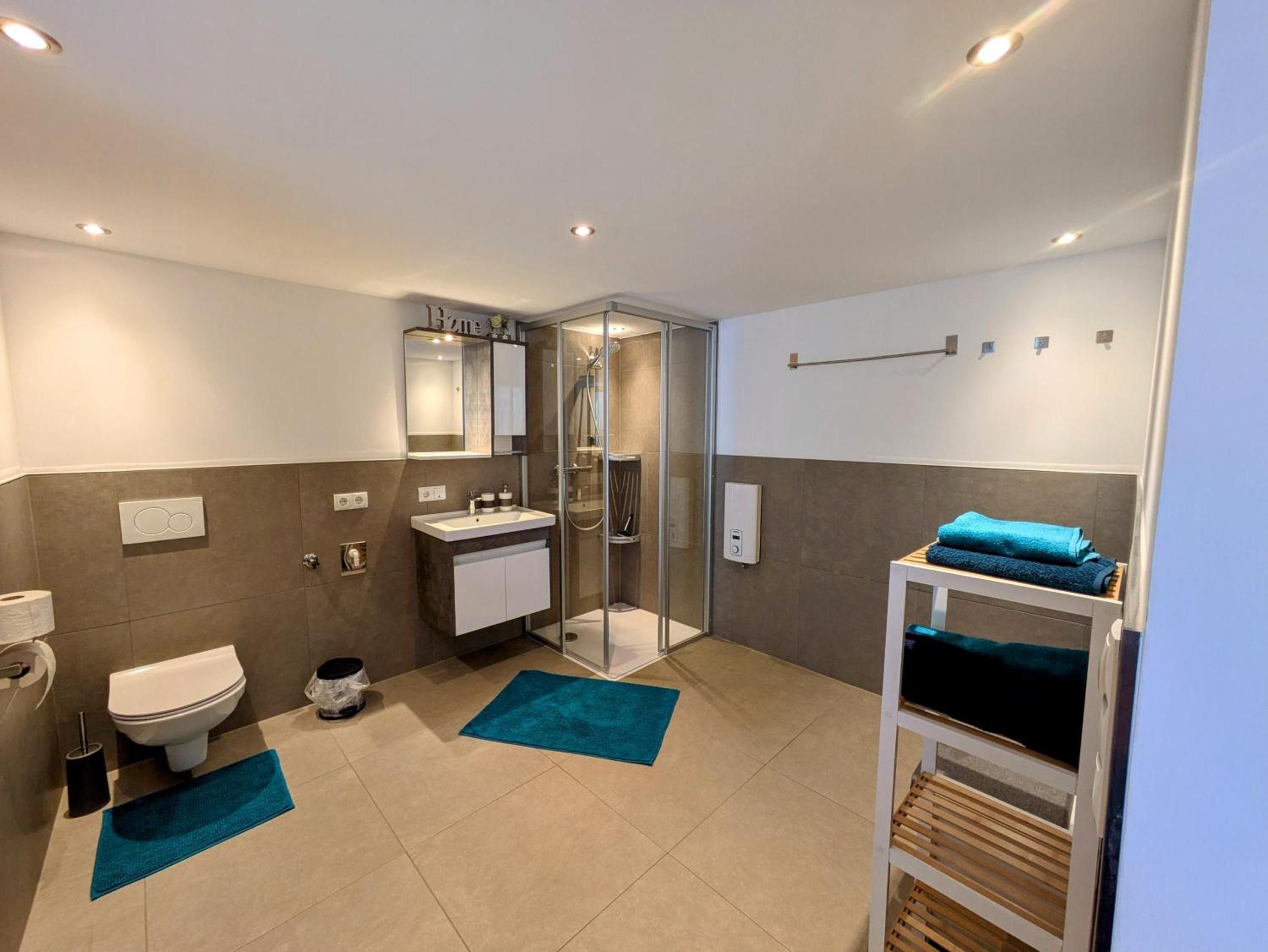 A modern bathroom with a glass shower enclosure, a white sink, and a towel rack.