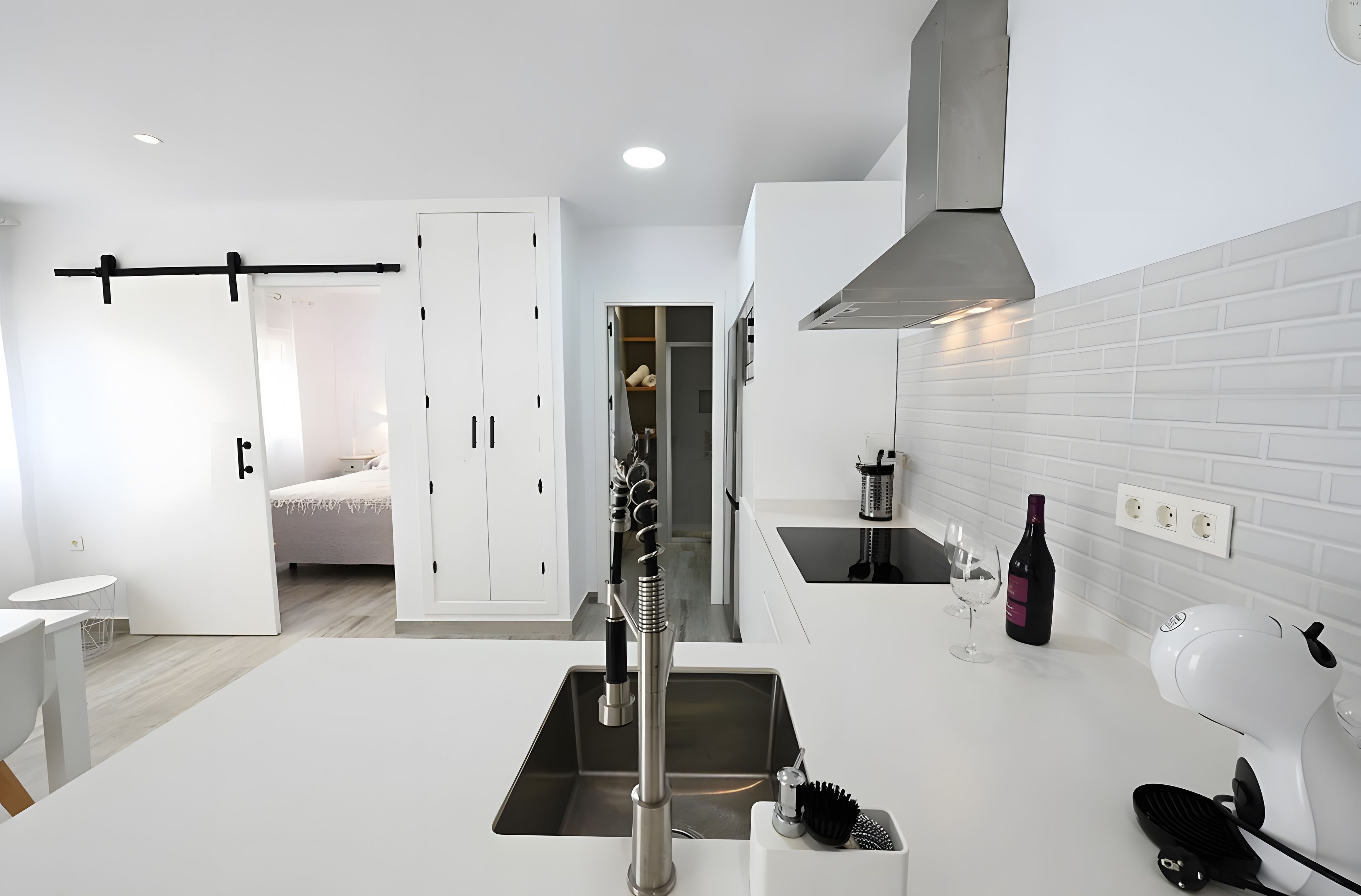 A modern kitchen with a central island, a built-in oven, and a hanging rack.