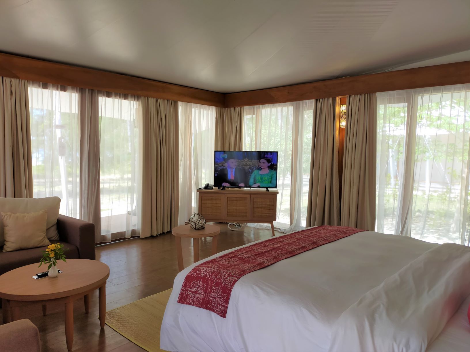 Una habitación de hotel con una cama grande, televisión, sofá y una mesita.