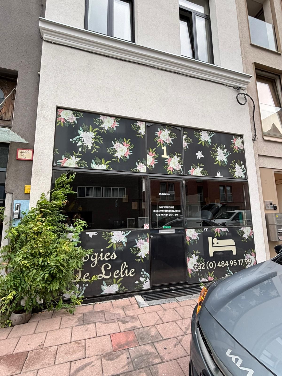 A building with a floral facade, a visible door, and a car parked in front.