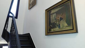 A staircase with a handrail and a painting of a domestic scene on the wall.