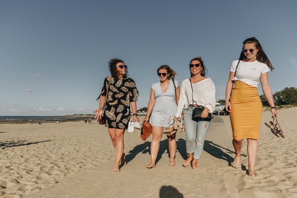 Quatro pessoas caminhando numa praia de areia.