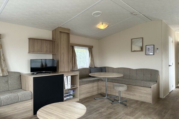 A compact living space with a sofa, a television, a small table, and a bookshelf.