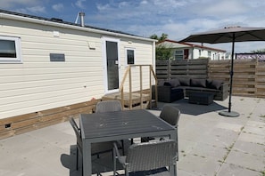 A mobile home with a patio area featuring a table, chairs, and a sofa set.