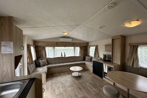 A compact RV interior with a kitchenette, seating area, and a dining space.