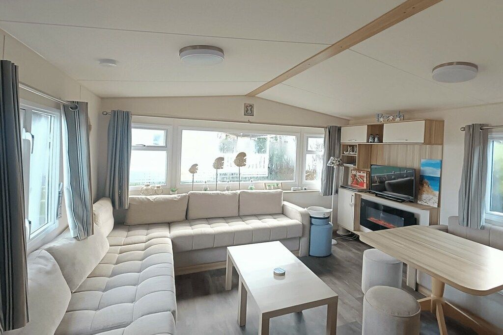 Ein modernes Wohnmobil-Interieur mit einer Sitzecke, Esstisch und einer Küchenzeile.