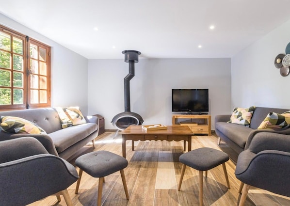 Una sala de estar moderna con chimenea, sofás, un televisor y una mesa de centro de madera.