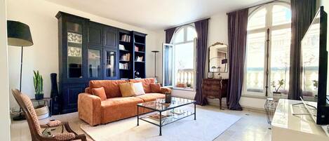 A living room with a sofa, armchair, coffee table, and a bookshelf.