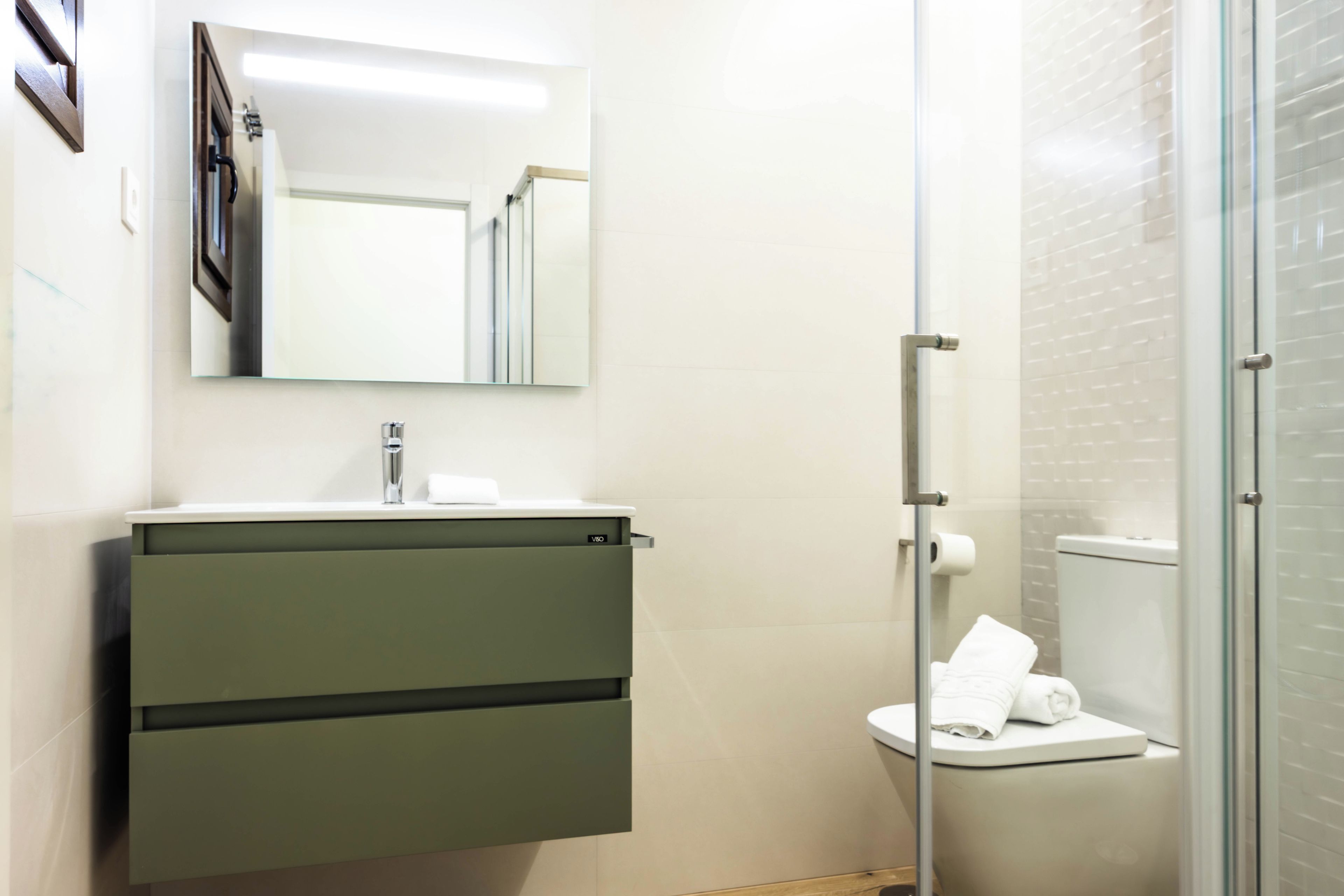 Een badkamer met een wastafel, spiegel en toilet.