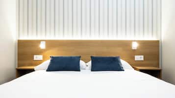 Quarto de hotel com uma cama grande, duas mesas de cabeceira e cabeceira de madeira.