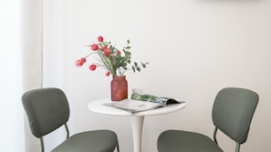 A small round table with a vase of flowers, a magazine, and two chairs. - Italianway Easy - Porta Nuova 52 D (Milan)