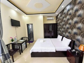 Een hotelkamer met een bed, een bureau, een stoel, een televisie en een airconditioning.