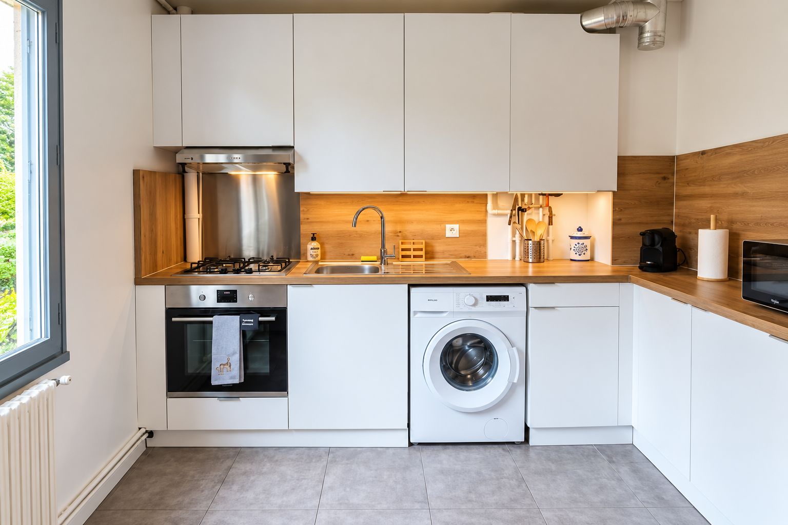 Una cucina moderna con piano cottura, forno, lavatrice e un bancone in legno.