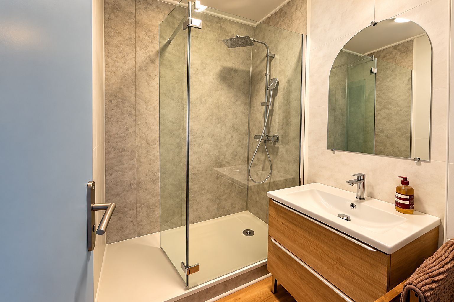 A modern bathroom with a glass-enclosed shower, a wooden vanity with a white sink, and a mirror above the vanity.