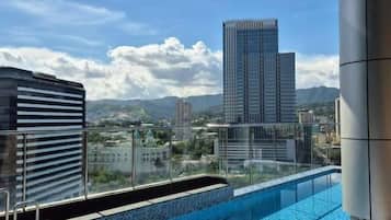 A rooftop pool with a city view, surrounded by buildings and a clear sky.
