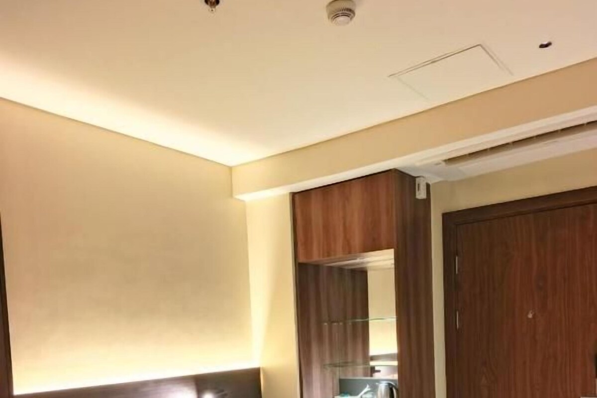 A hotel room with a bed, a nightstand, a mirror, and a wooden wardrobe.