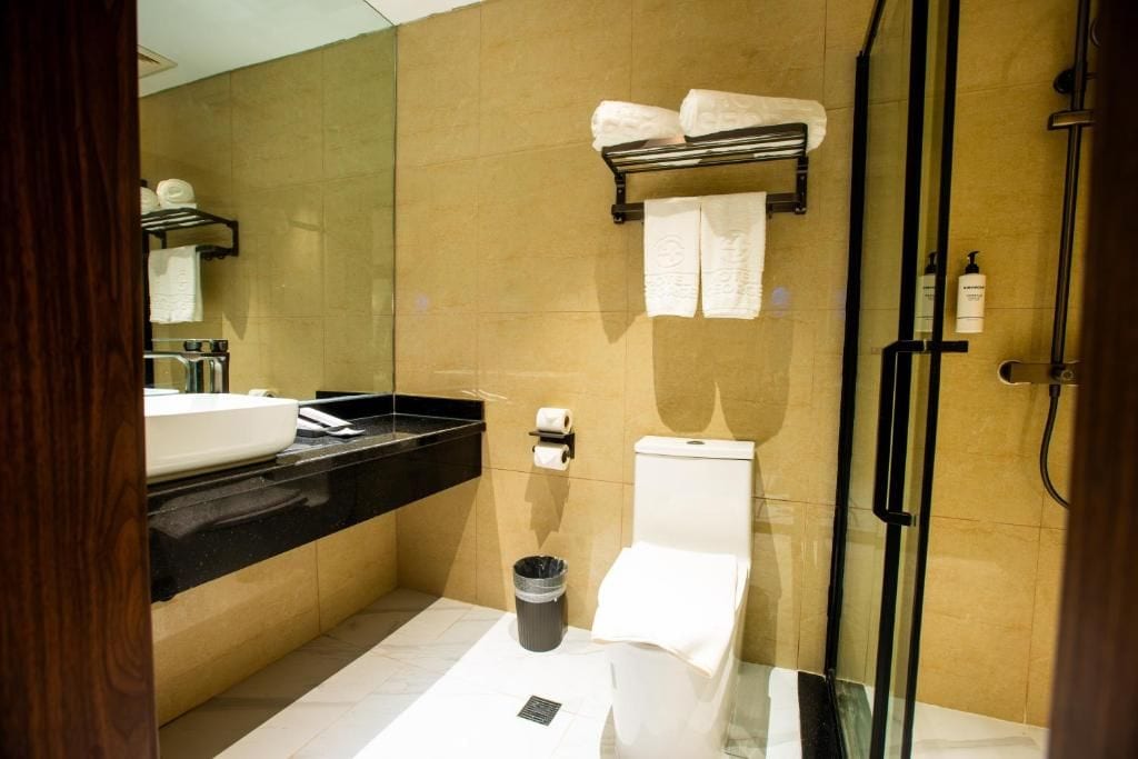 Un baño moderno con cabina de ducha de vidrio, lavamanos con encimera negra y un inodoro.